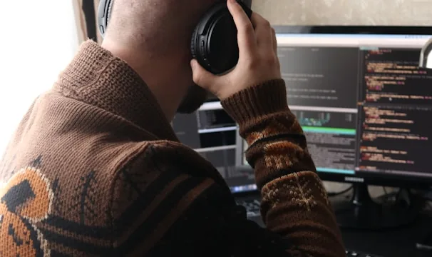 a man sitting in front of a computer with headphones on